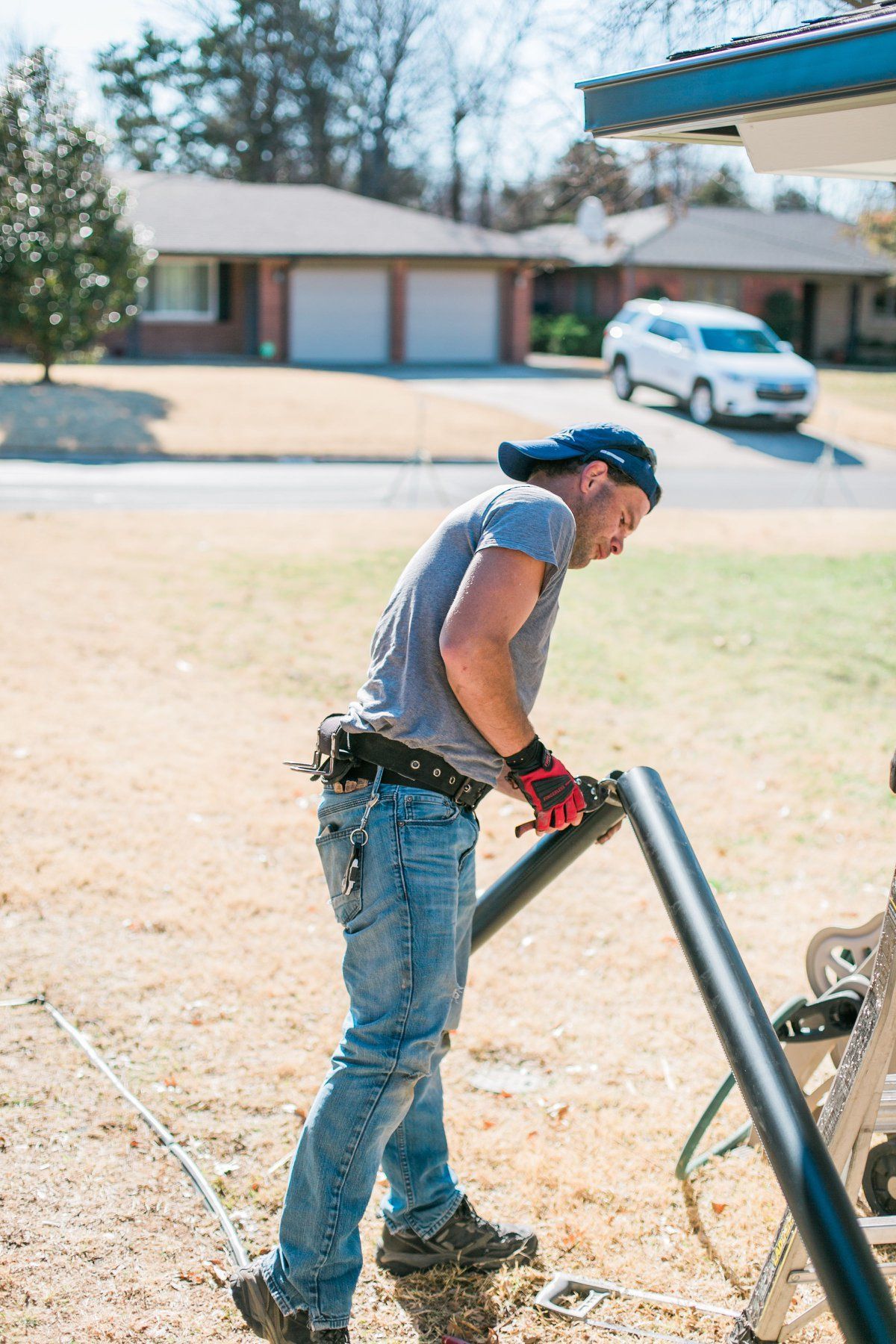 A man is working on a pipe outside of a house.