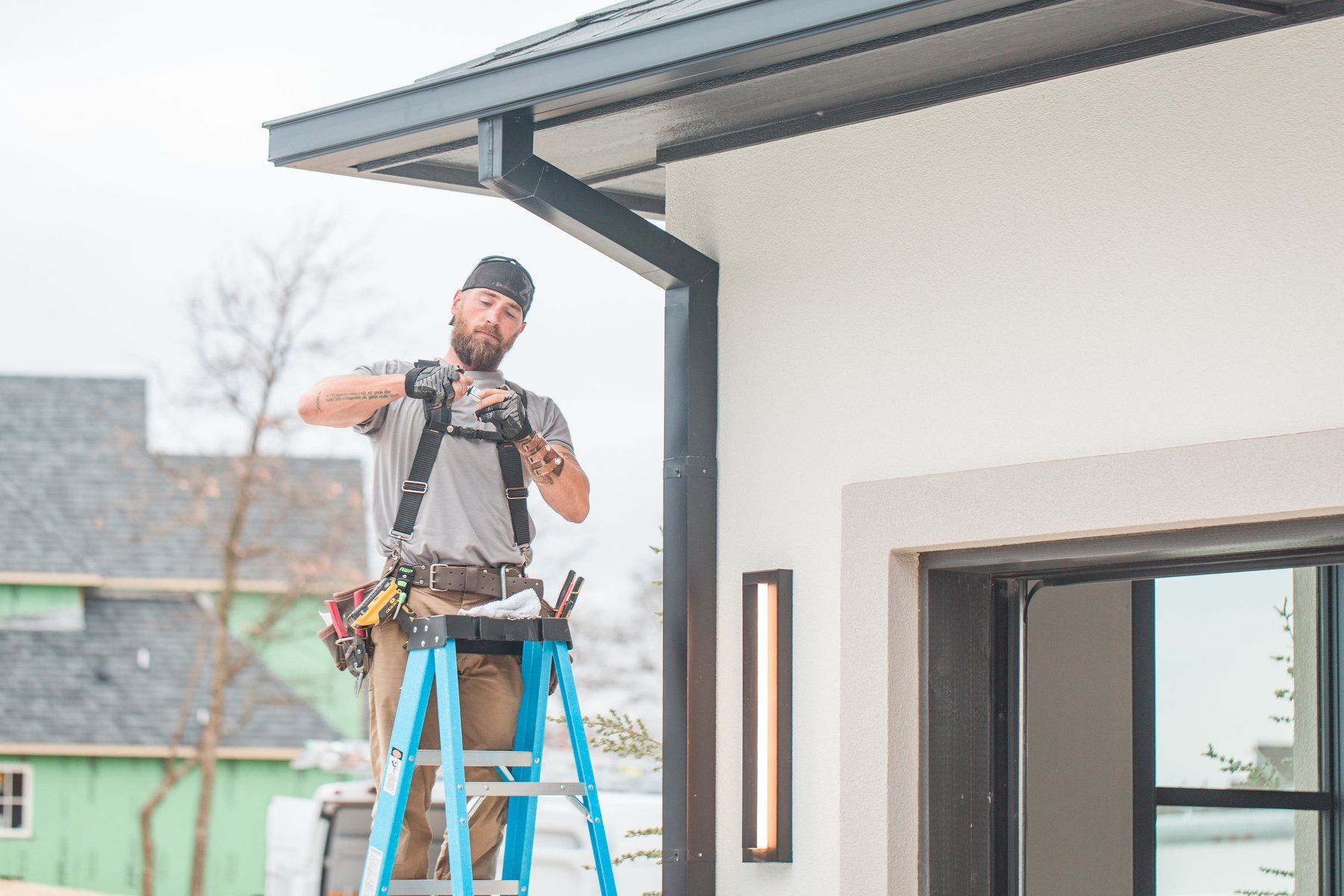 A man is standing on a ladder in front of a house.