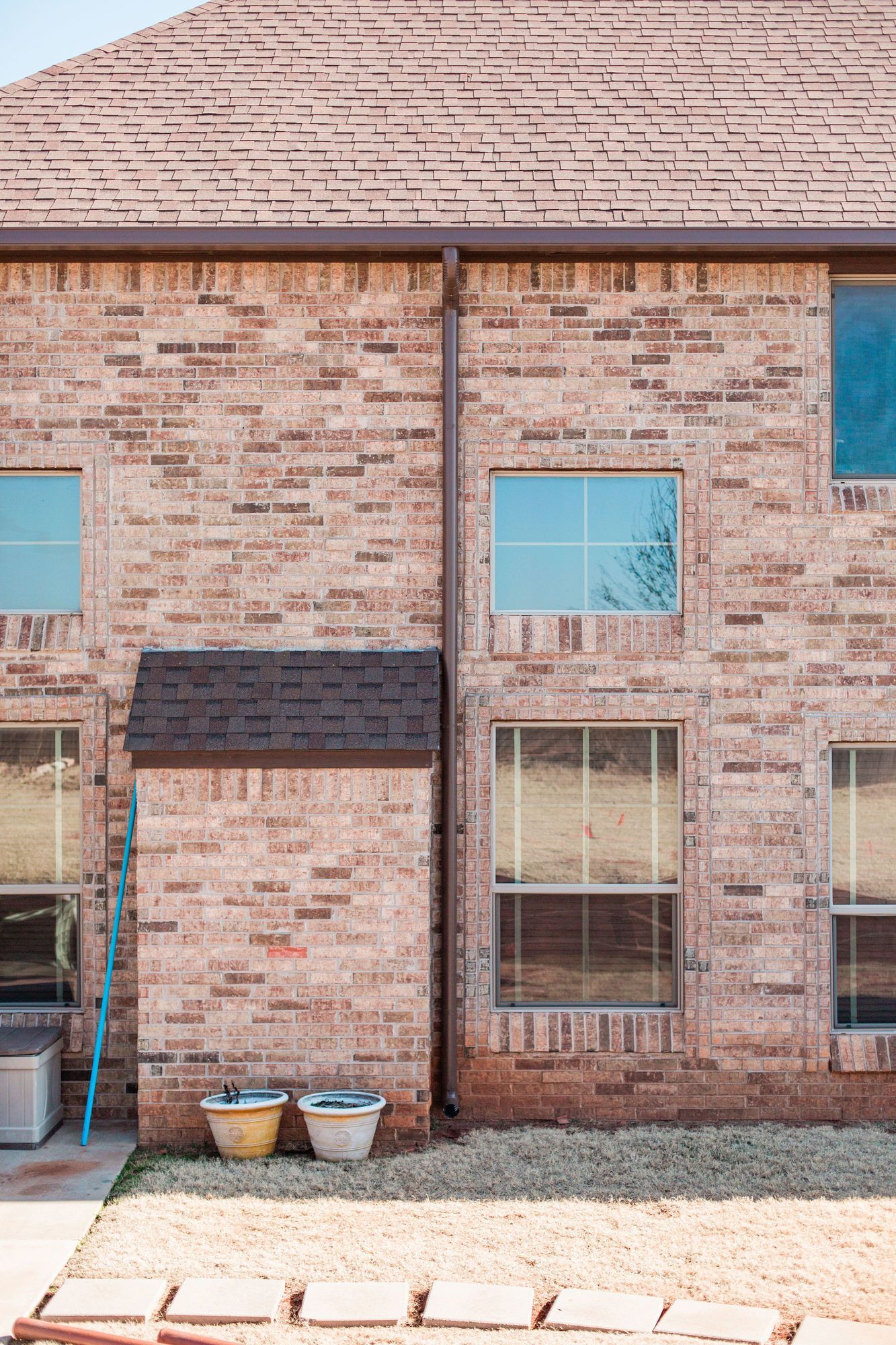 A brick house with a lot of windows and a ladder in front of it.