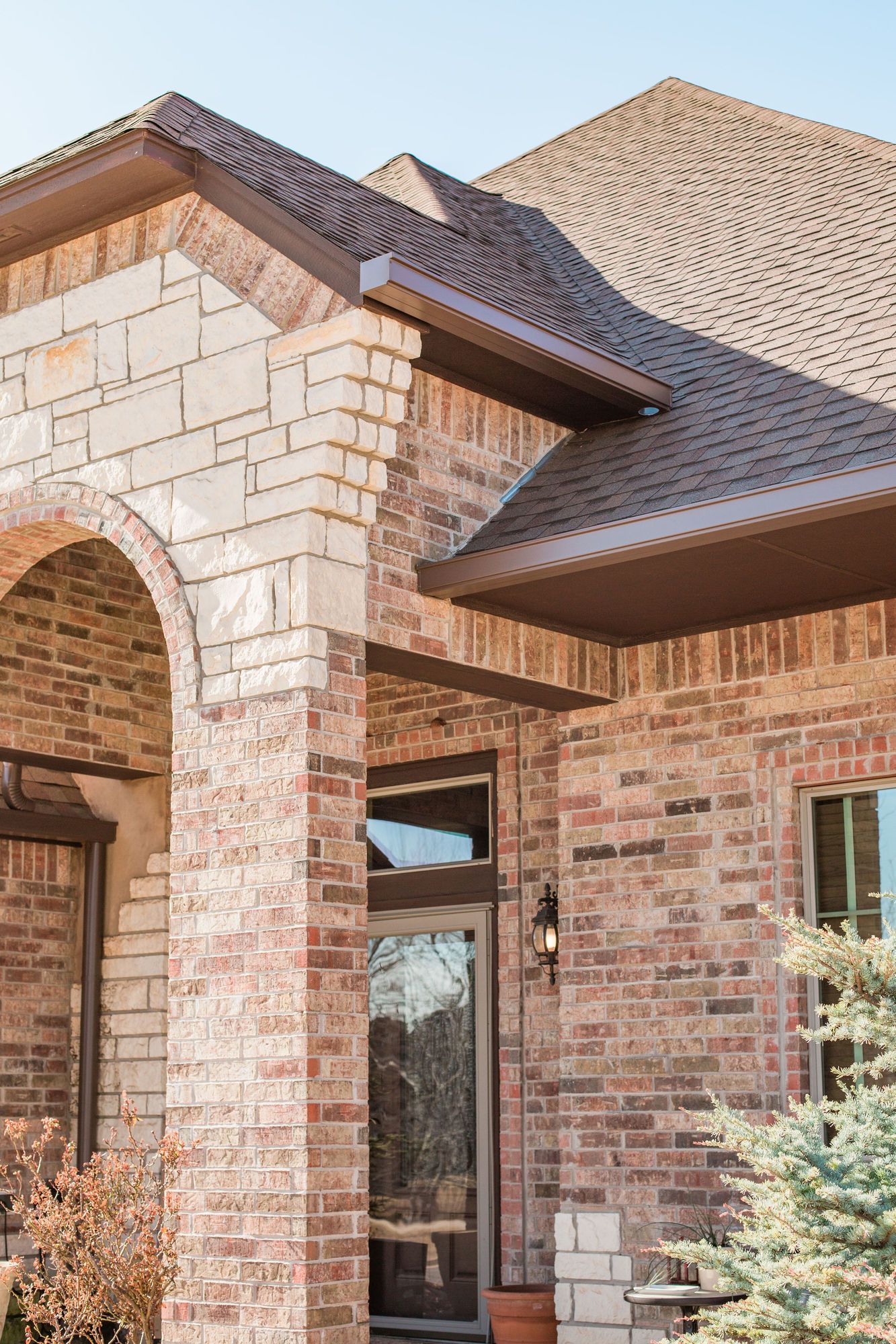 A large brick house with a brown roof and a porch.