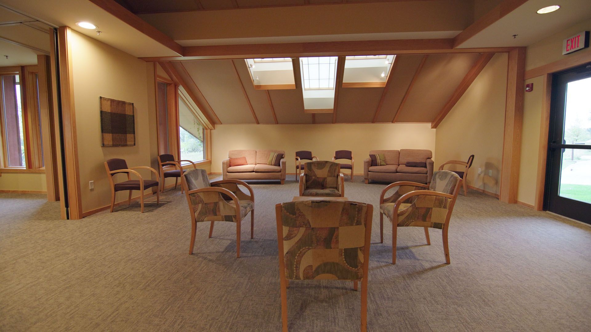 A room with a circle of chairs, sofas, and natural light.