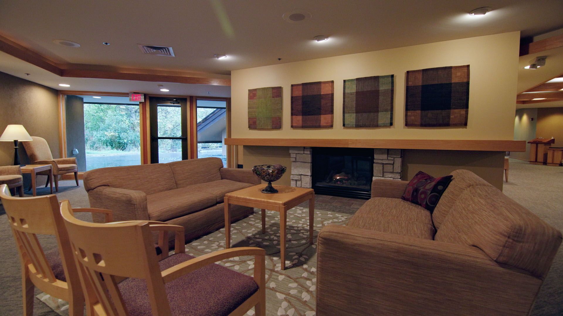 Cozy seating area with sofas, chairs, fireplace, and artwork; a doorway to the outdoors.