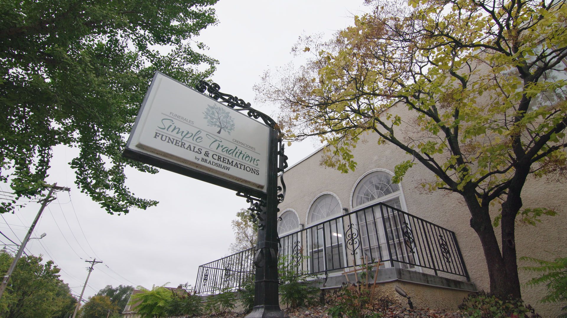 Sign for Temple Shalom with a brick building and trees in the background.