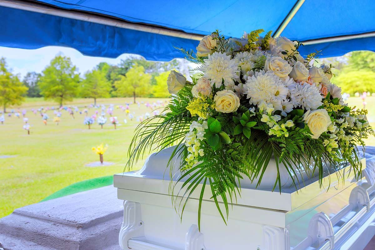 A group of people are standing around a coffin at a funeral.