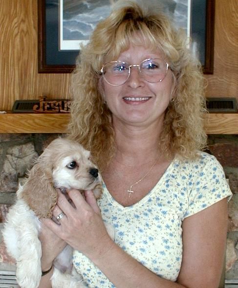 A woman is holding a puppy in her arms and smiling