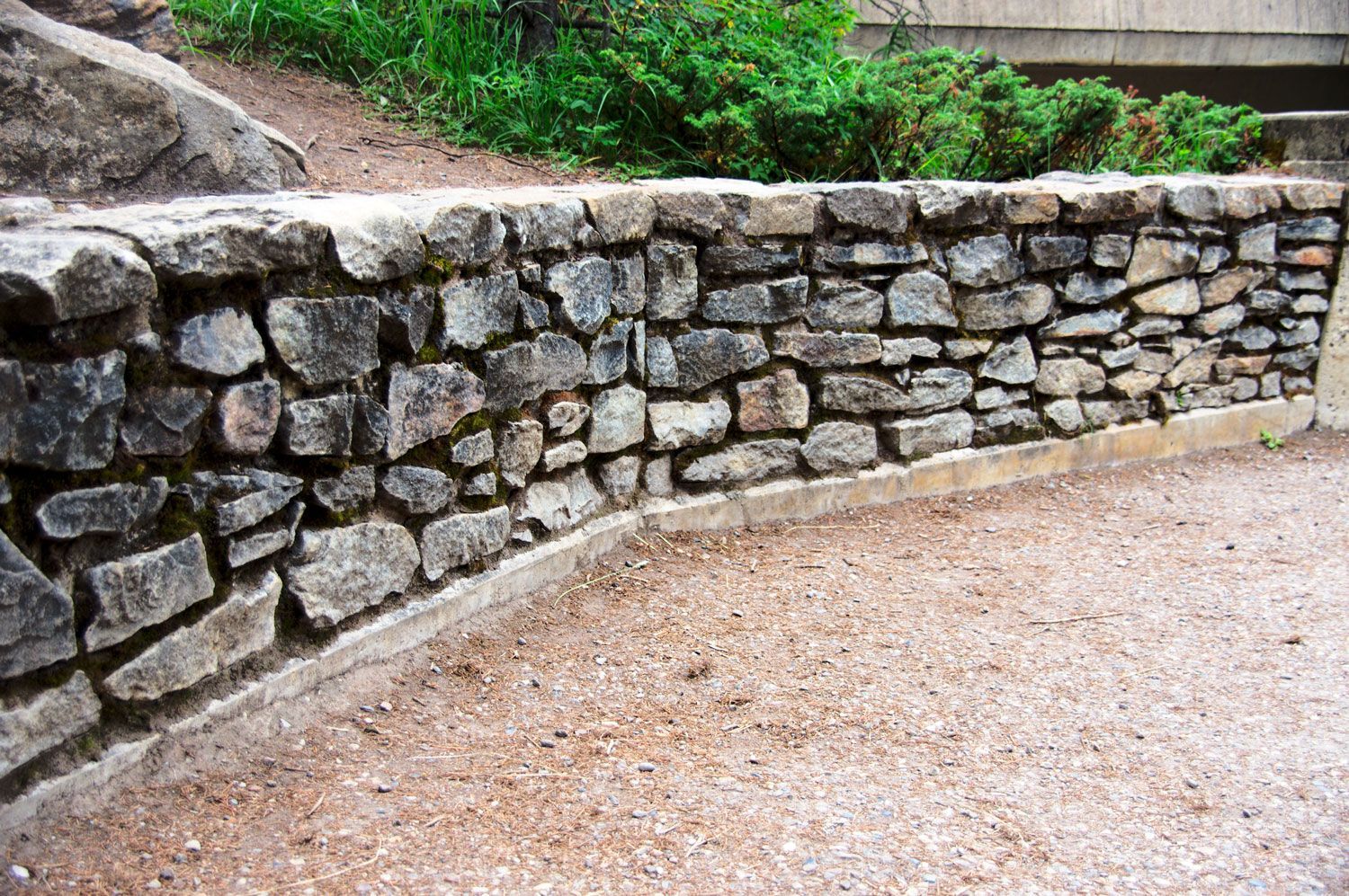 A Stone Wall Surrounded By Gravel And Grass — Youngsville, NC — Dontavius Landscaping