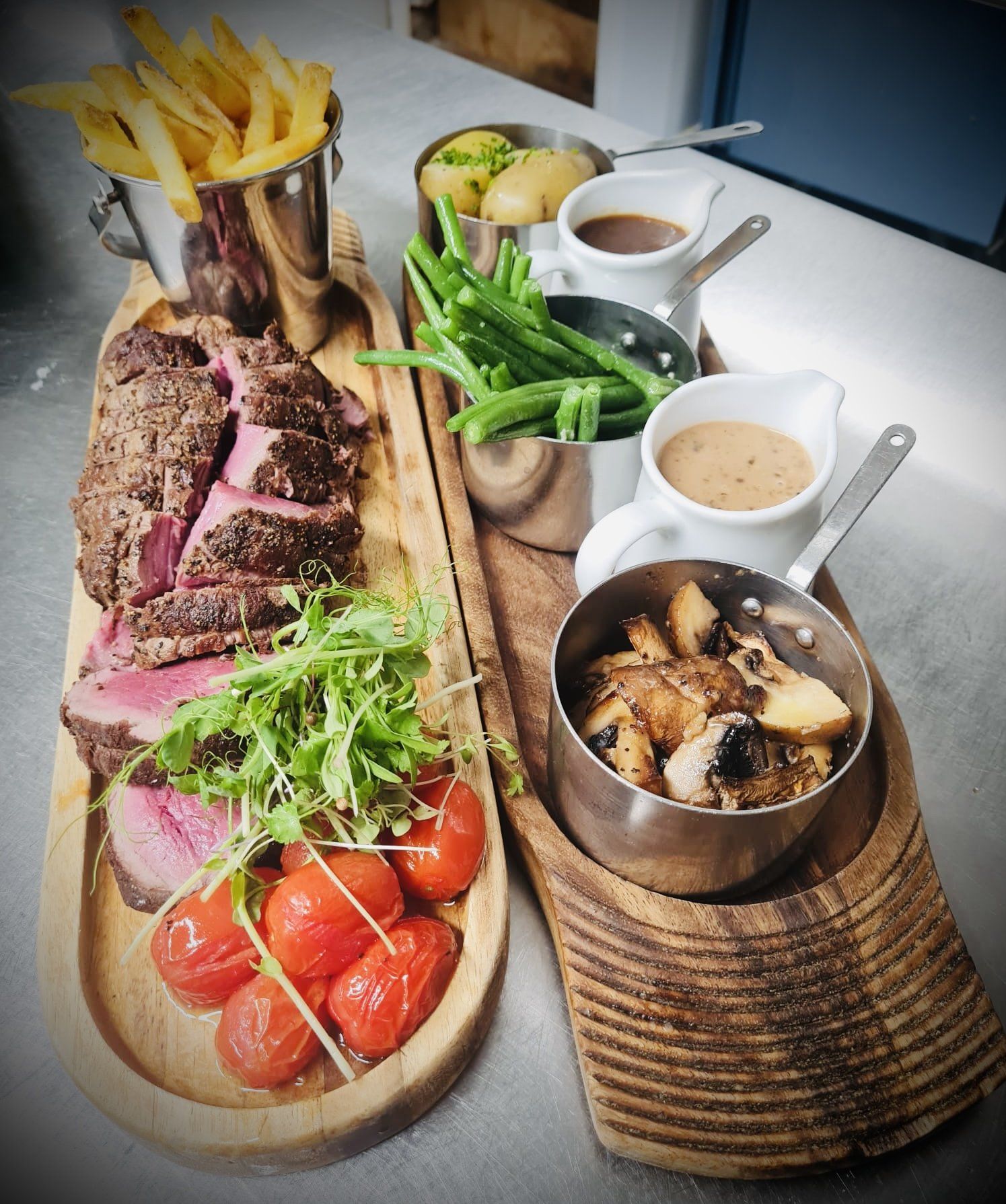 A wooden cutting board topped with meat , vegetables and sauces.