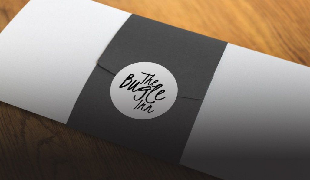A white and black envelope with a sticker on it that says bugle inn