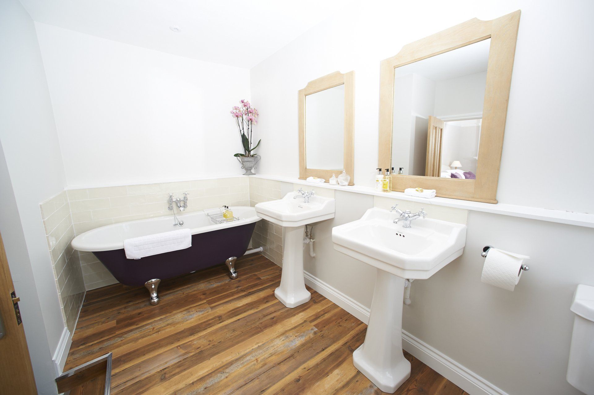 A bathroom with a purple tub and two sinks