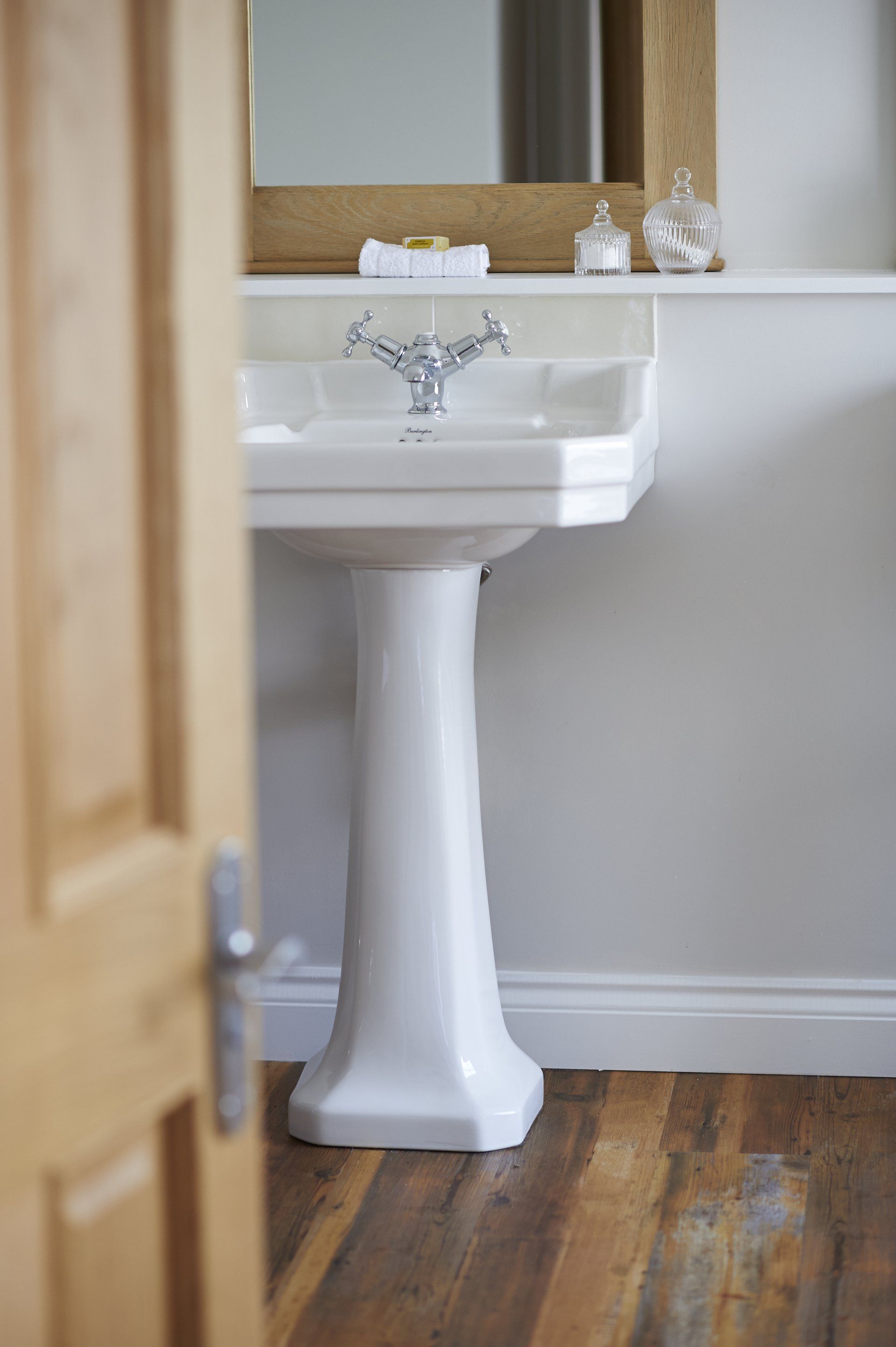 A bathroom with a pedestal sink and a mirror.