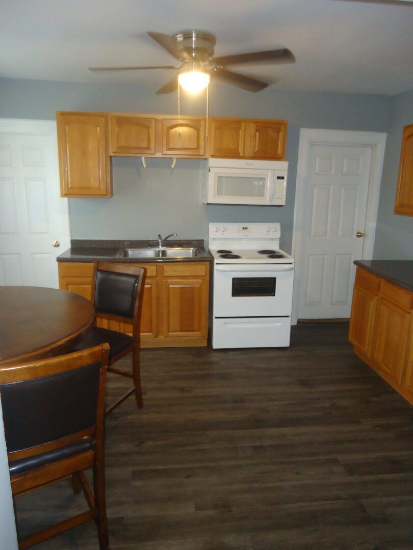 A kitchen with a table and chairs and a ceiling fan