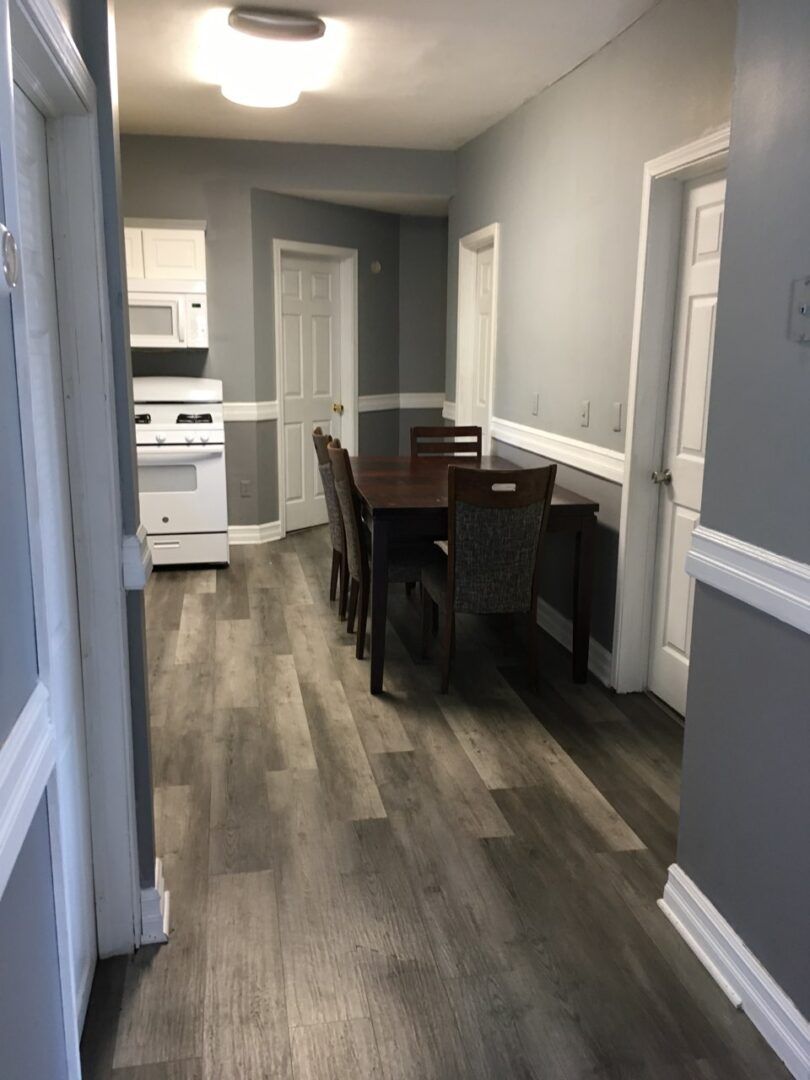 A hallway leading to a kitchen with a table and chairs