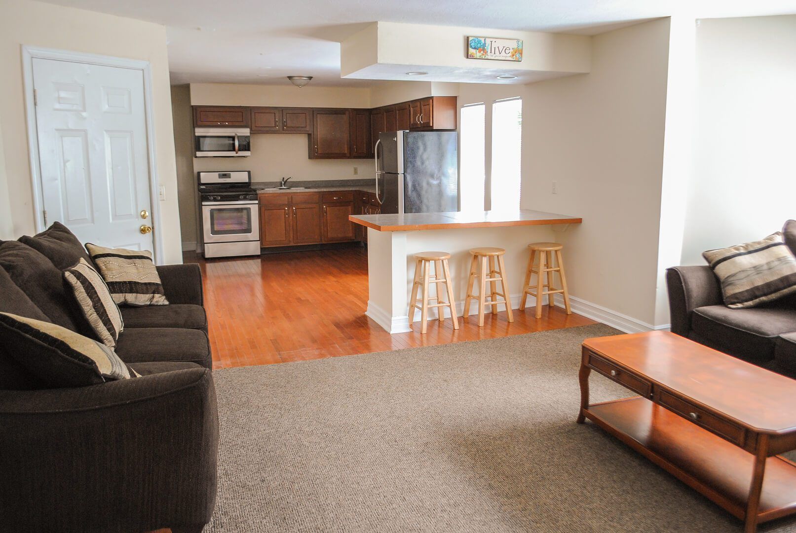 A living room with a couch and a coffee table and a kitchen in the background