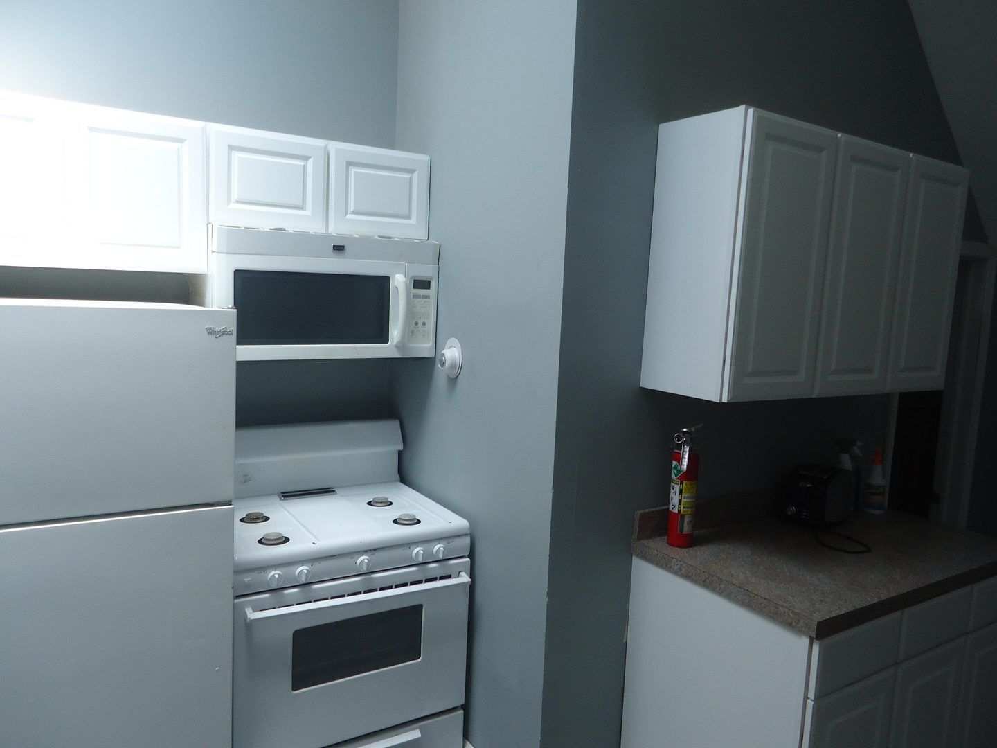 A kitchen with a stove a refrigerator and a microwave