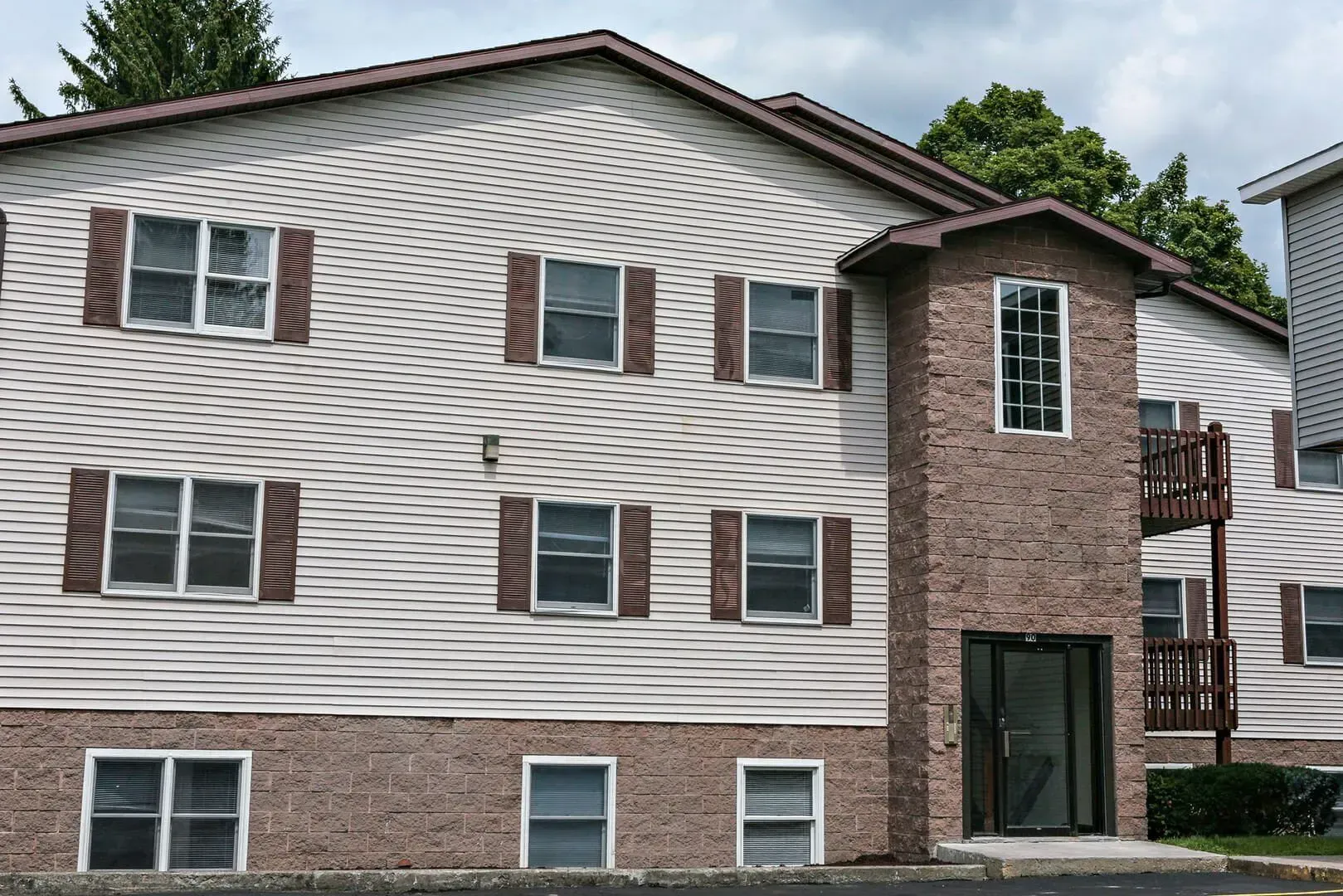 A large apartment building with white siding and brown shutters