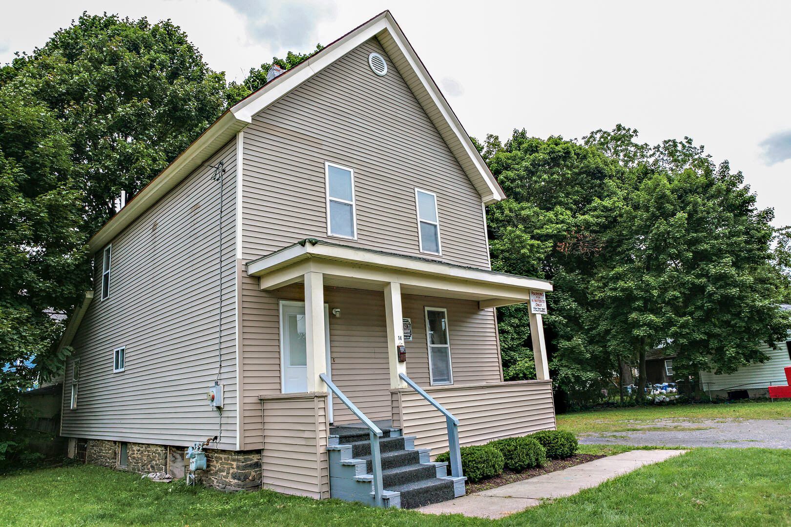 A small house with a porch and stairs in front of it