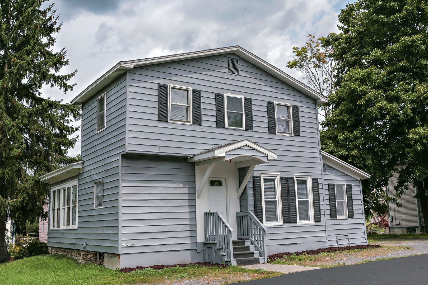 A large gray house with black shutters and stairs