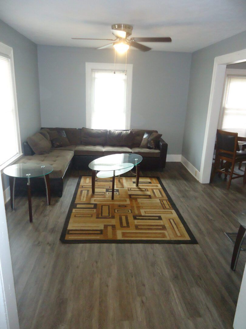 A living room with a sectional couch and a ceiling fan