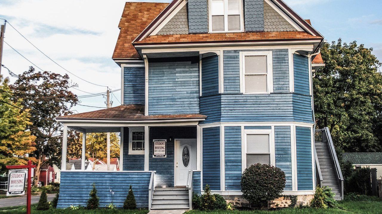 A large gray house with black shutters and stairs