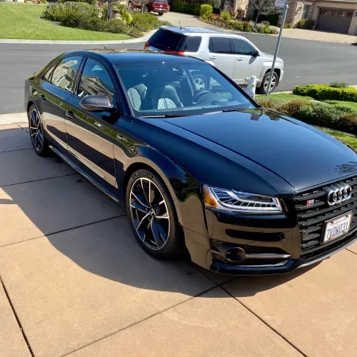 a black audi is parked on the side of the road .