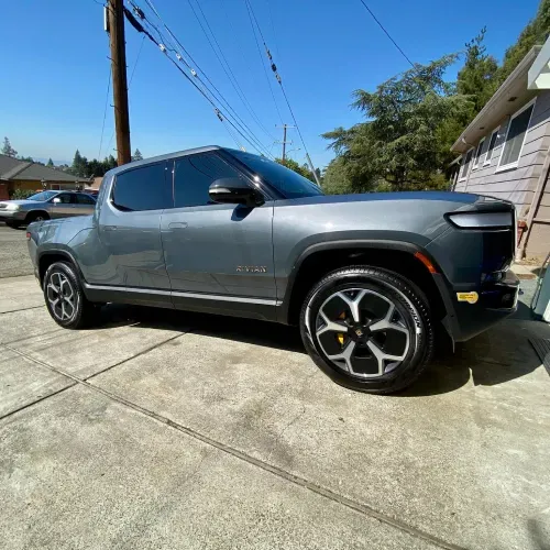 a gray truck is parked in a driveway next to a house .