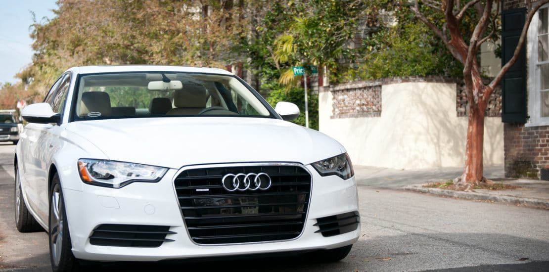 A white audi is parked on the side of the road.