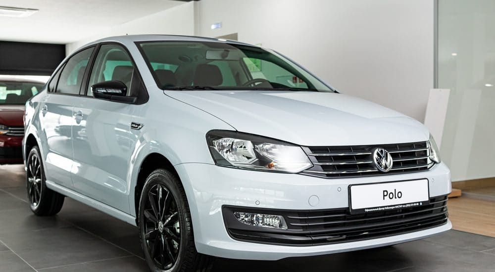 A white volkswagen polo is parked in a showroom.