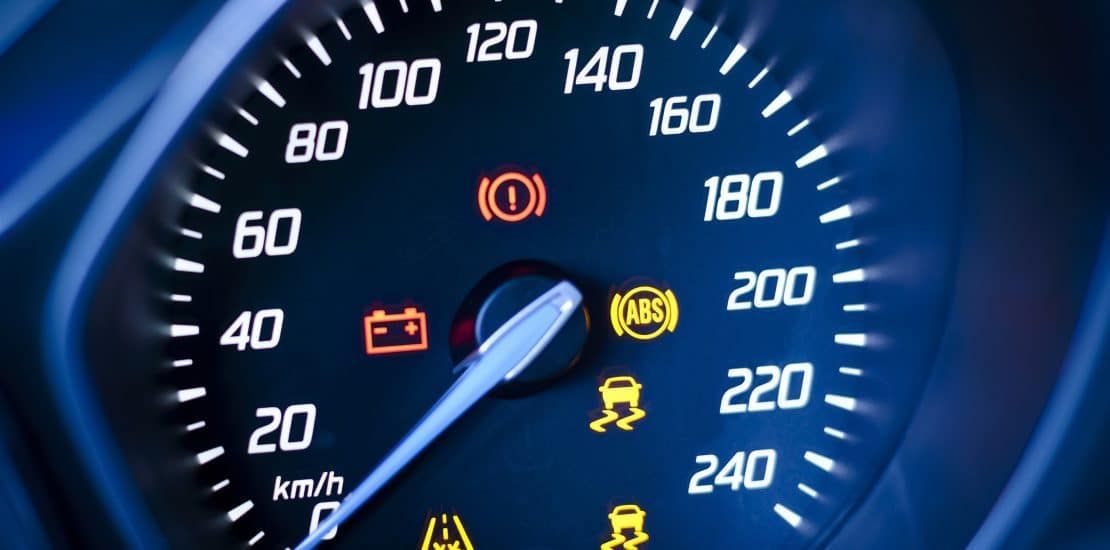 A close up of a speedometer with various warning lights on it