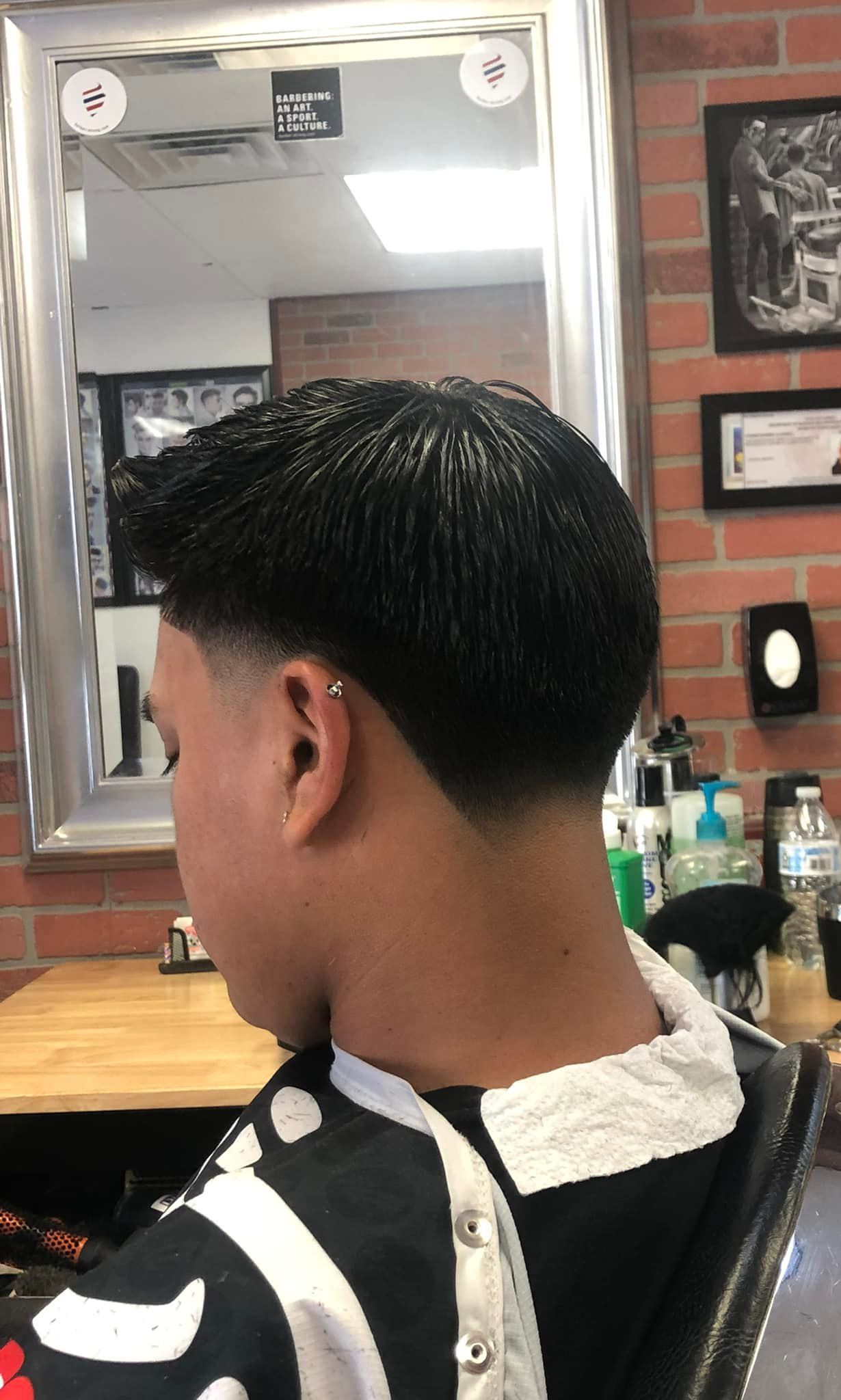 A man is getting his hair cut at a barber shop.