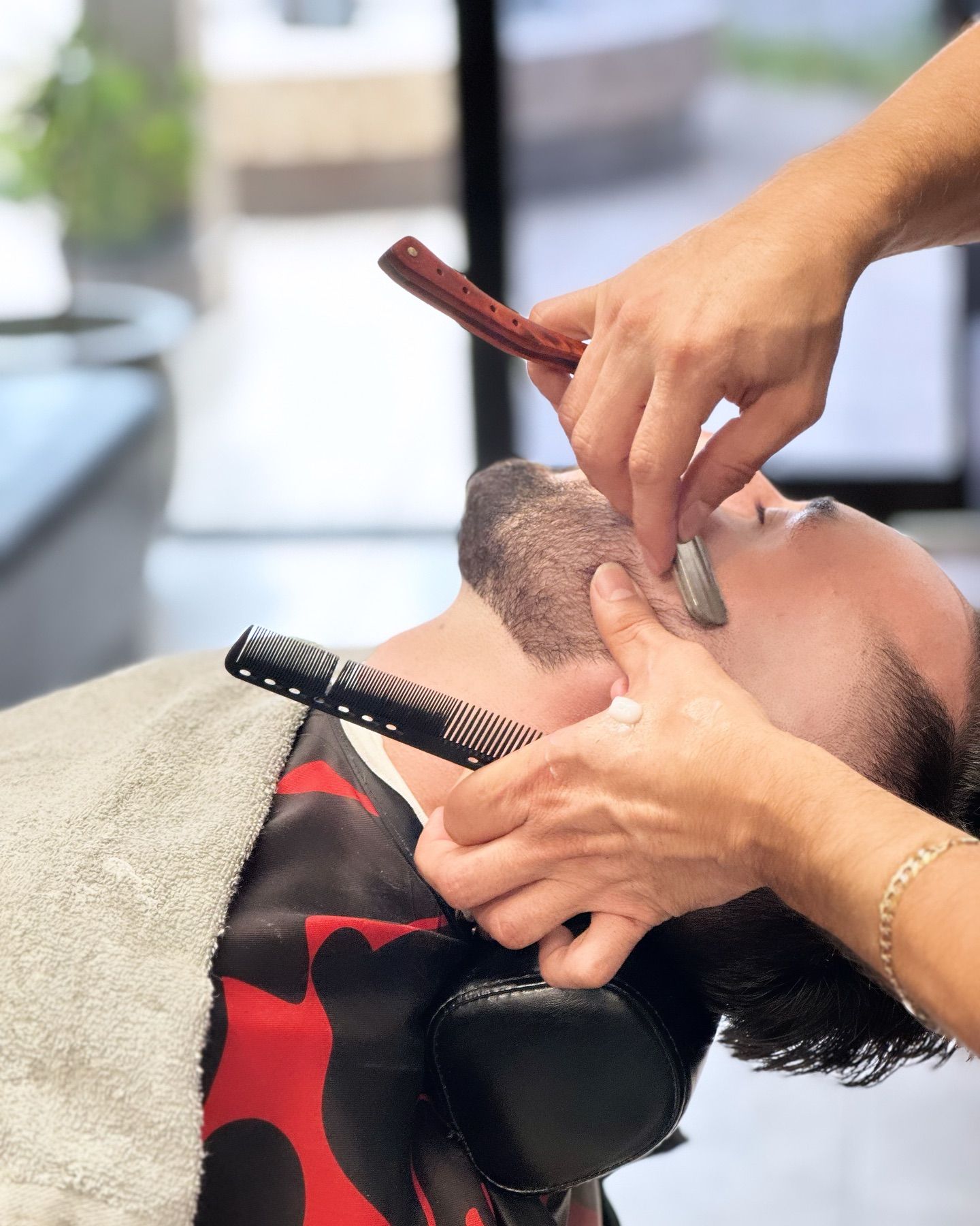 A man is getting his beard shaved at a barber shop.