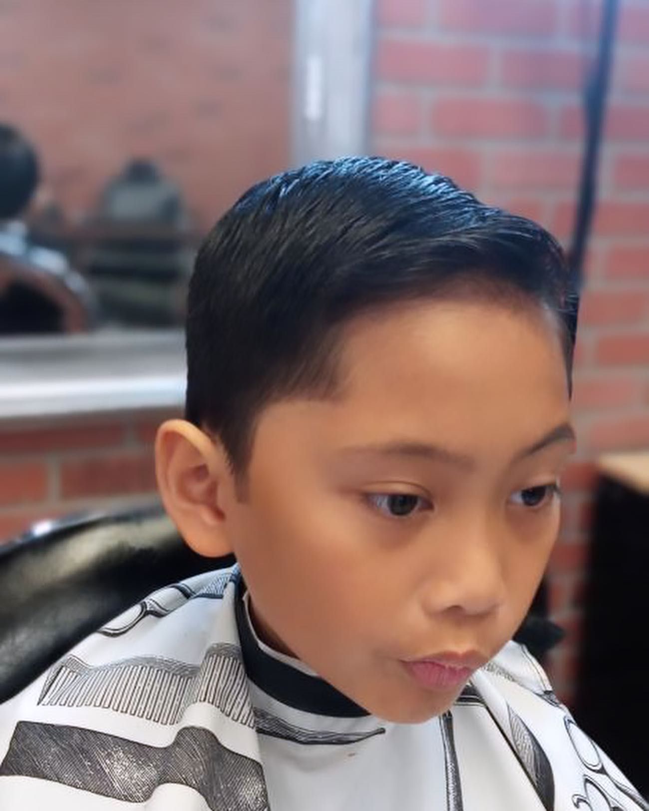 A young boy is getting his hair cut at a barber shop