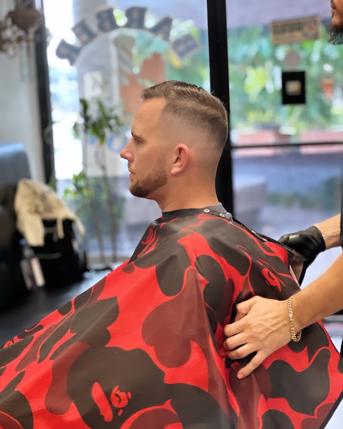 A man is getting his hair cut at a barber shop.