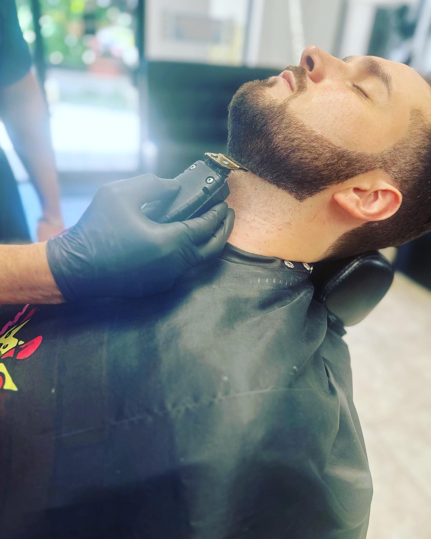 A man is getting his beard shaved at a barber shop.