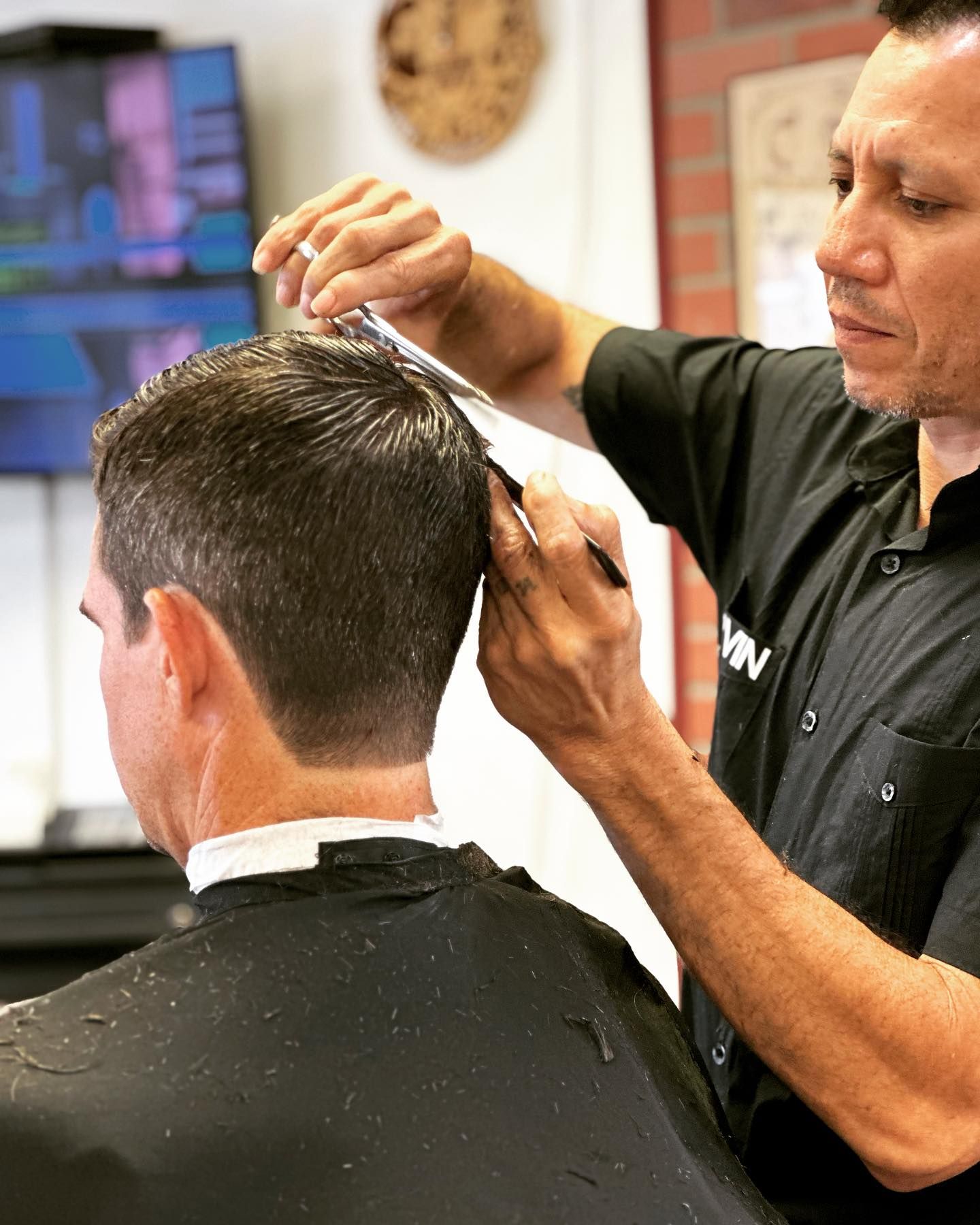 A man is getting his hair cut by a barber in a barber shop.