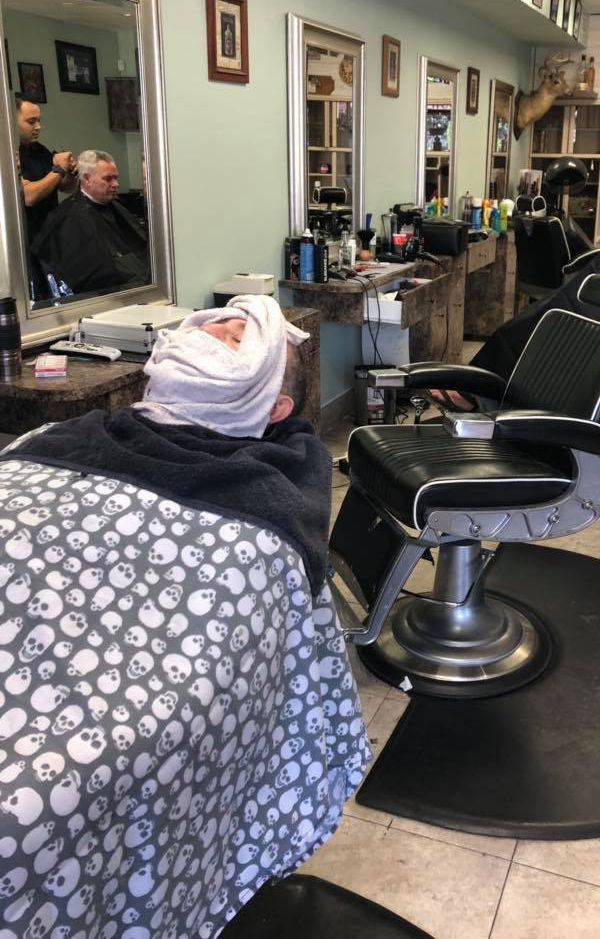 A man is getting his hair cut at a barber shop.