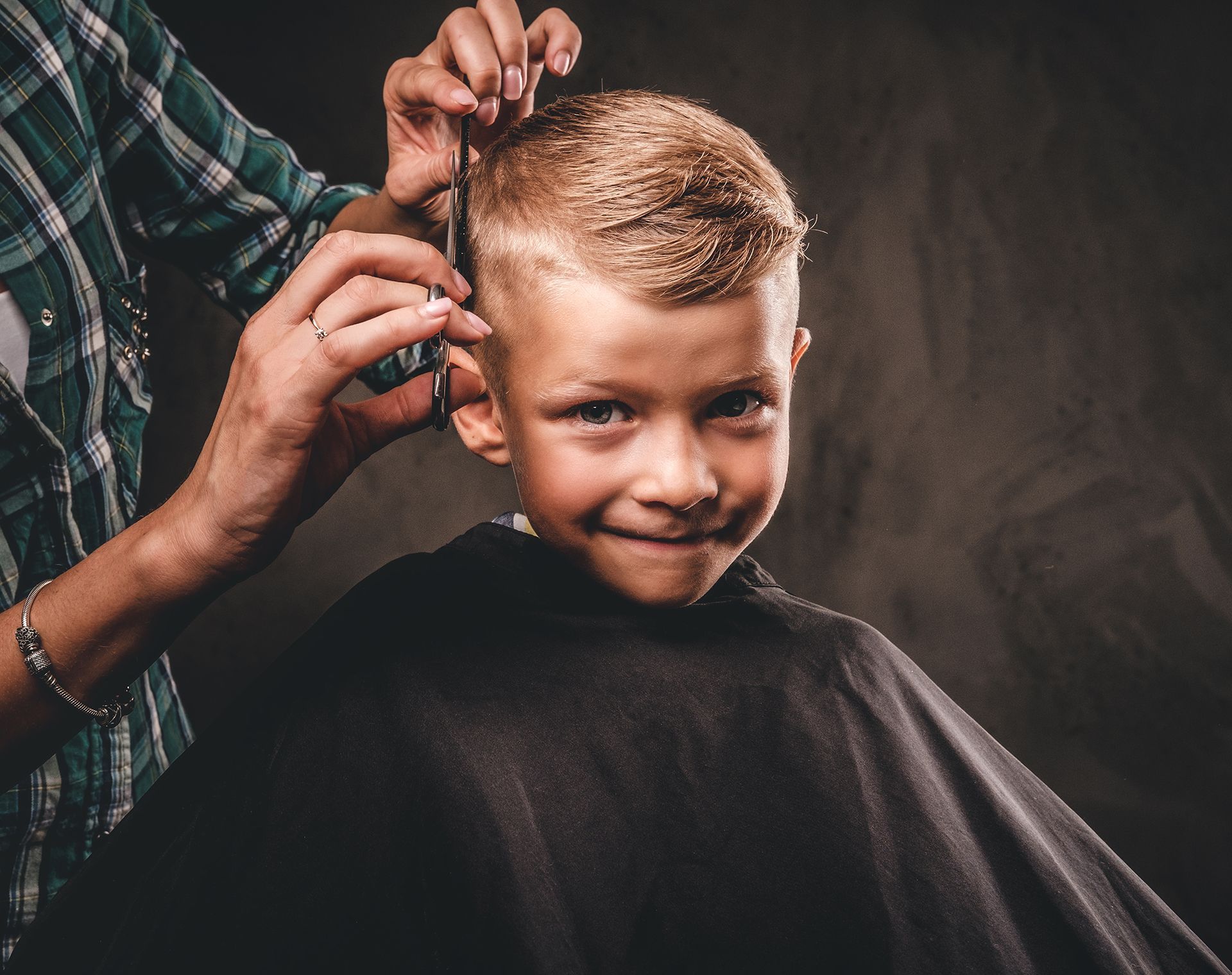A young boy is getting his hair cut by a barber.