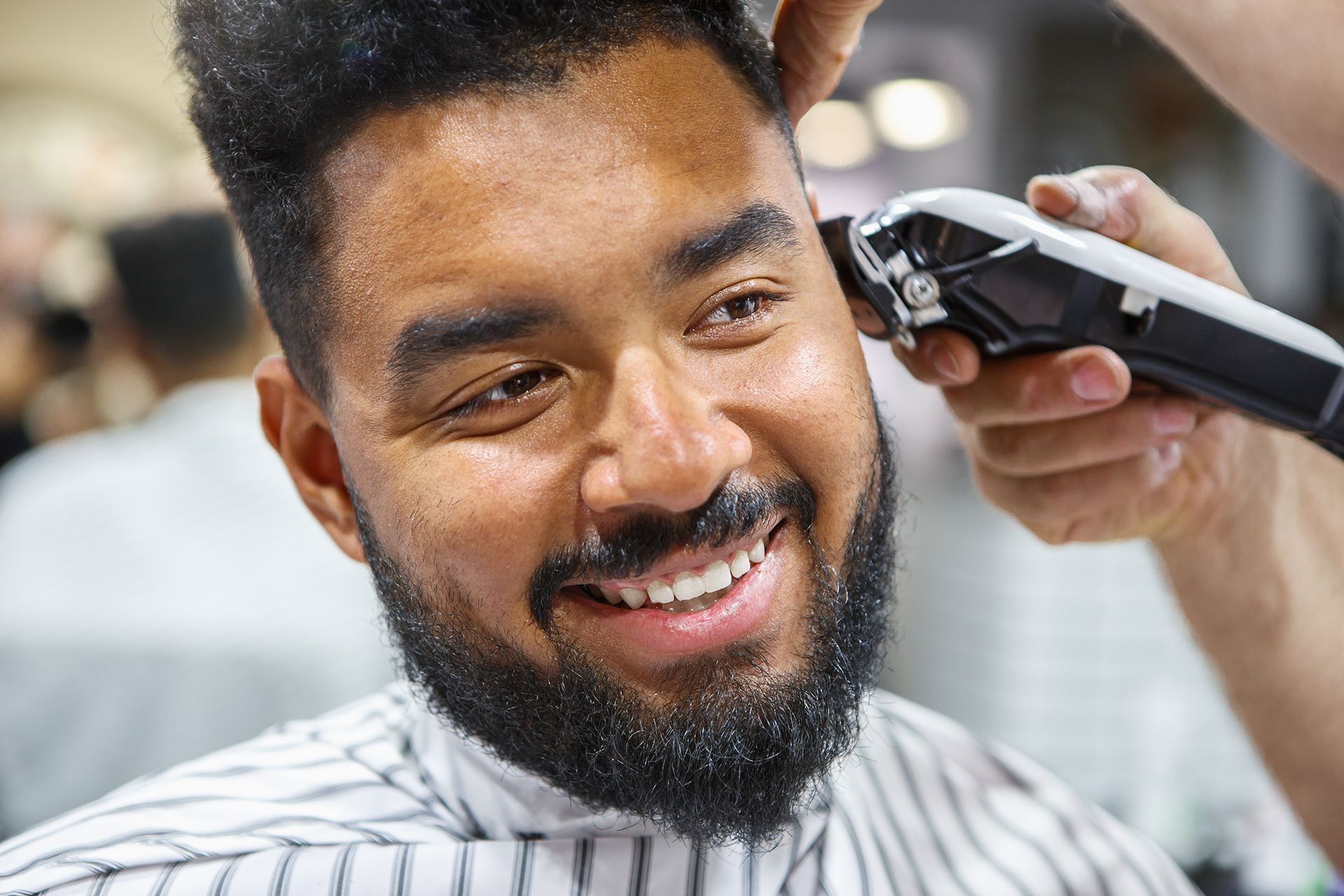 A man with a beard is getting his hair cut by a barber.