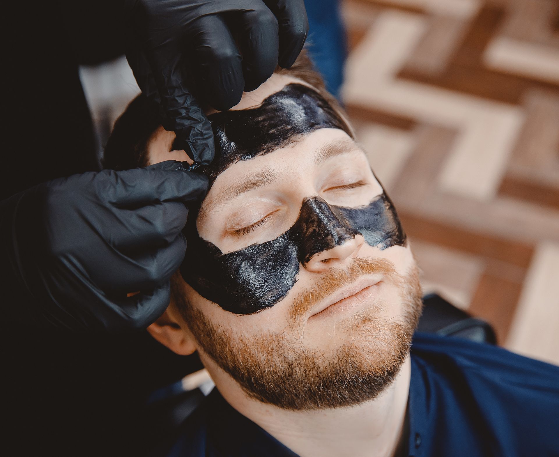A man is getting a black mask on his face.