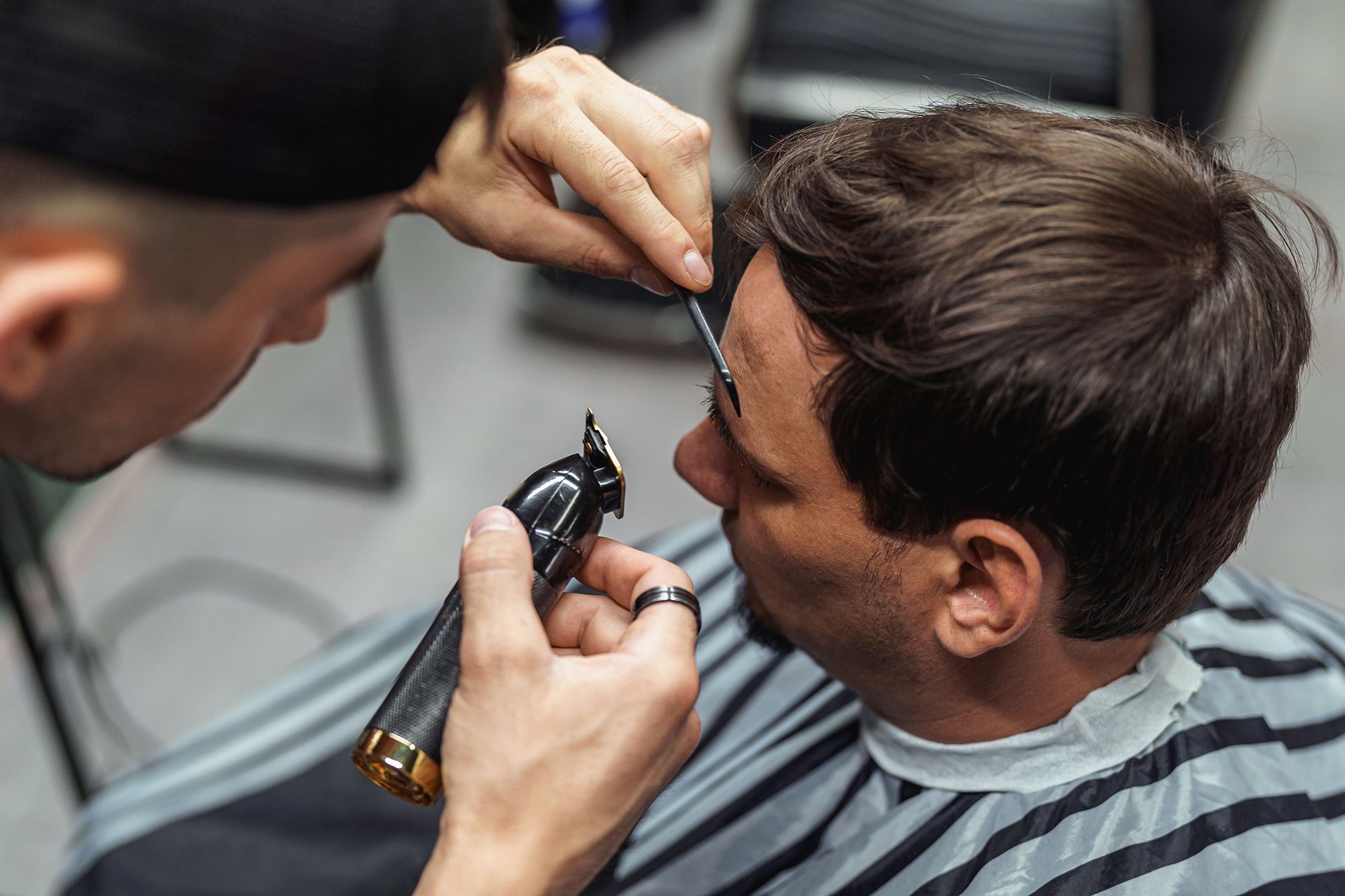 A man is getting his hair cut by a barber in a barber shop.