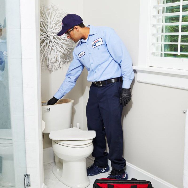 Man in a Blue Shirt Standing Next to a Toilet - Apple Valley, CA - Roto-Rooter Plumbers and Septic Service
