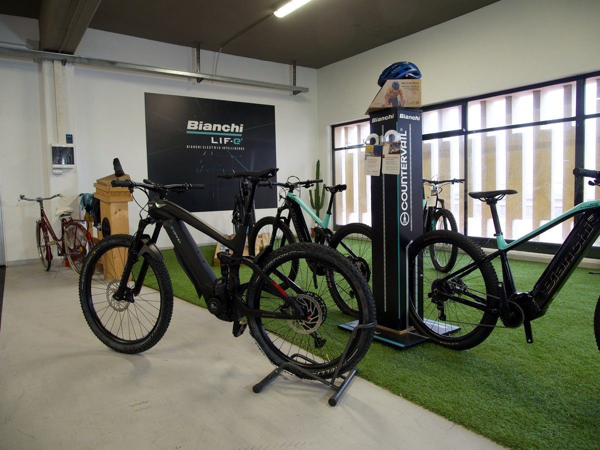 Uno showroom Bianchi con diverse mountain bike elettriche esposte su una superficie interna in erba sintetica.