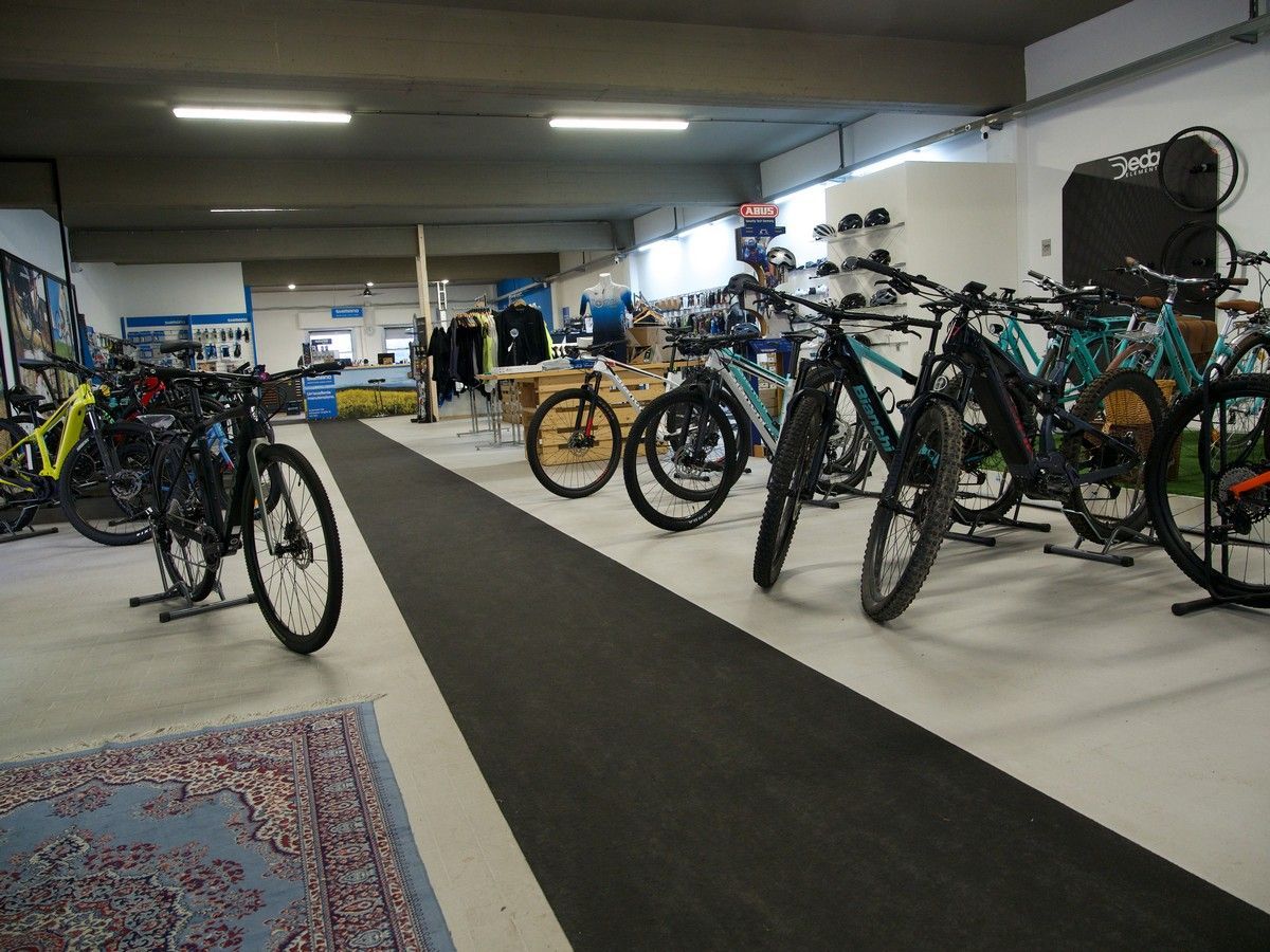 Interno di un negozio al dettaglio con diverse mountain bike parcheggiate in fila su un tappetino.