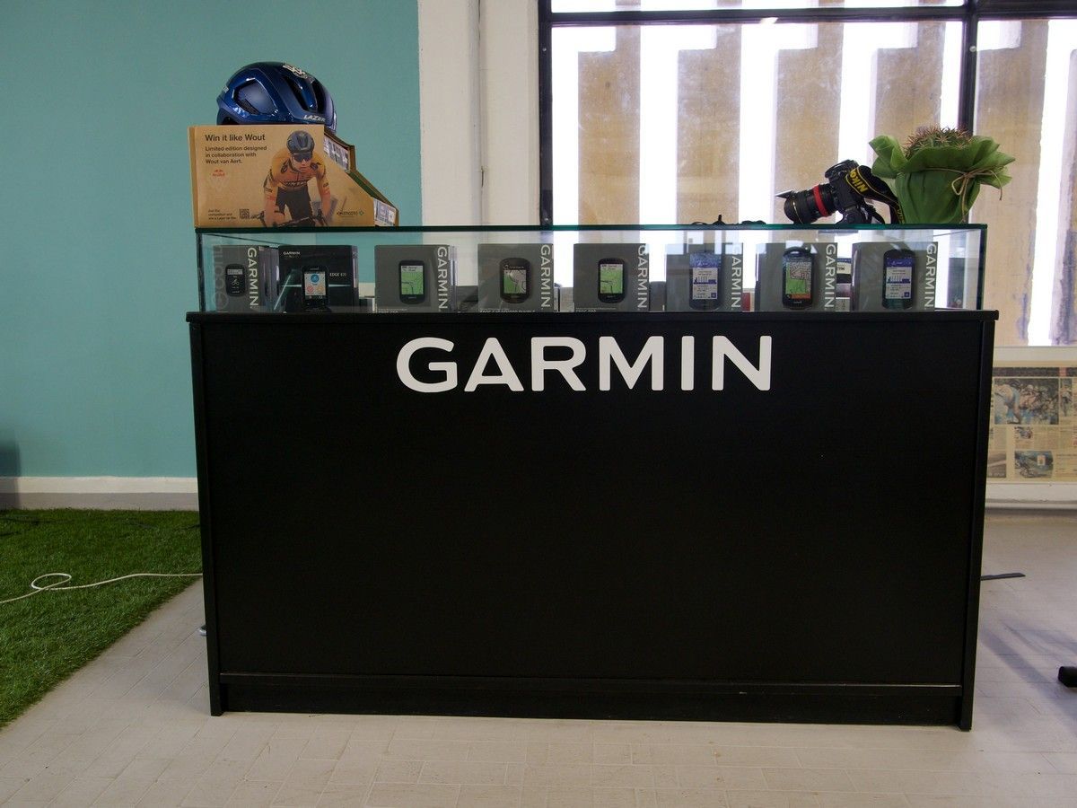 Un bancone espositivo nero della Garmin con diversi dispositivi GPS allineati in una teca di vetro all'interno di un negozio.