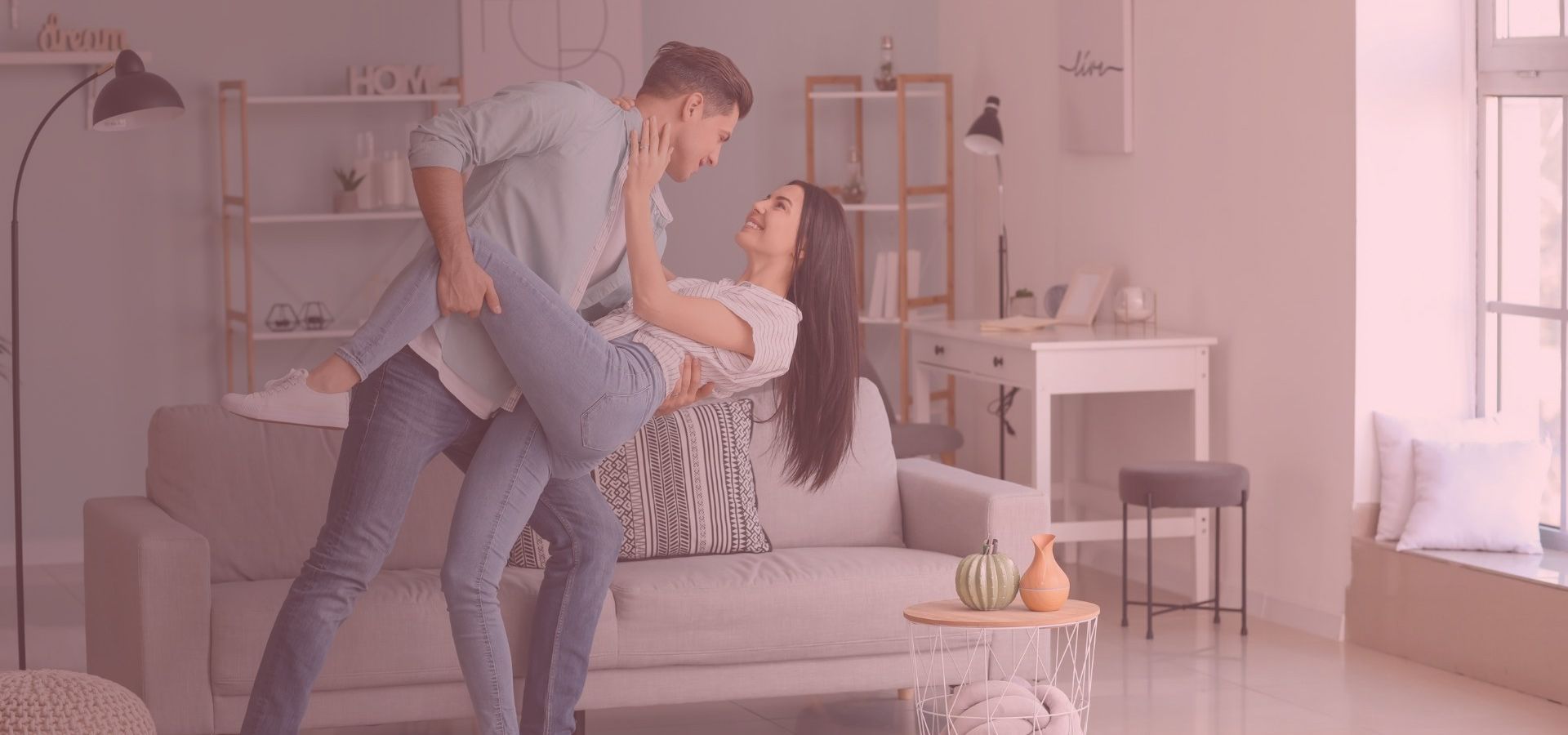 A couple dances in a living room. The man holds the woman, who leans back smiling. Sunlight streams in.