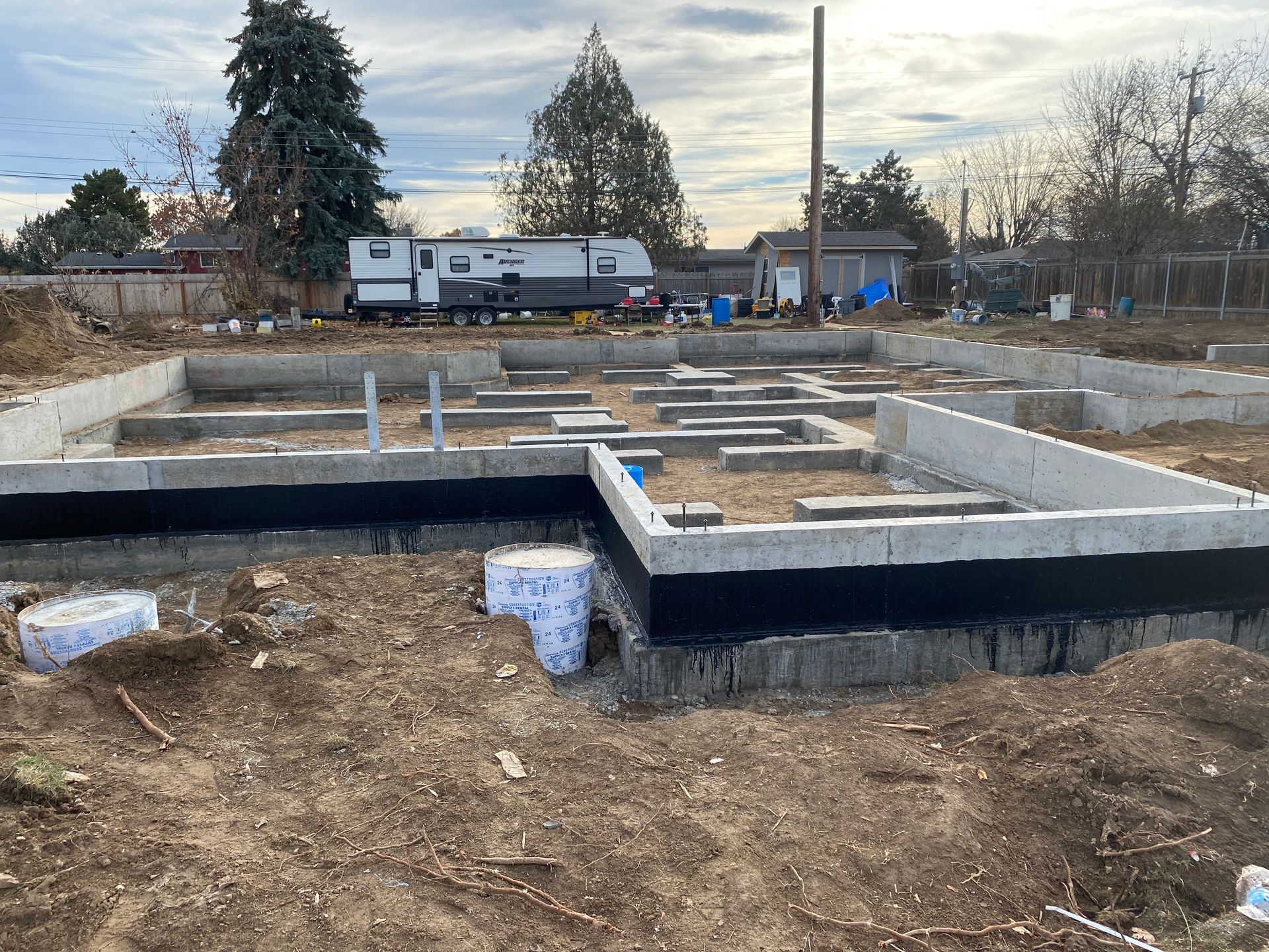 Concrete foundation for a building in a construction site. Black sealant applied to outer walls.