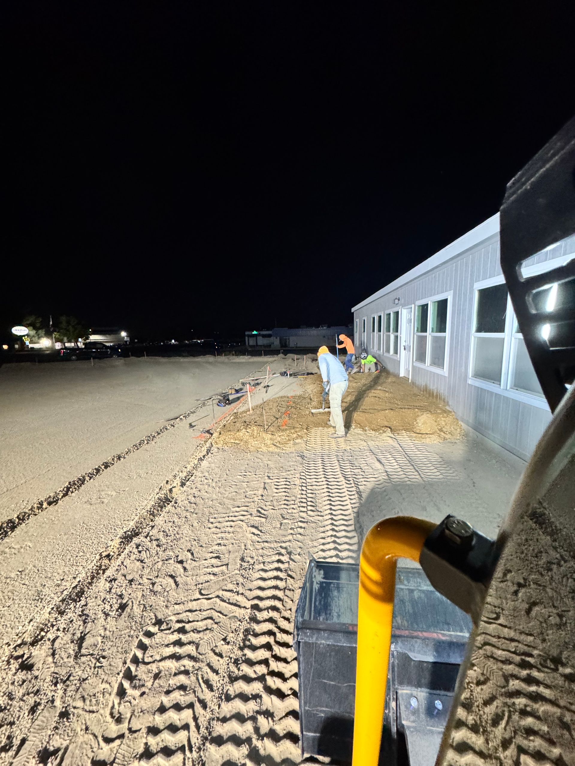 Construction site at night. Workers near a building with heavy machinery.