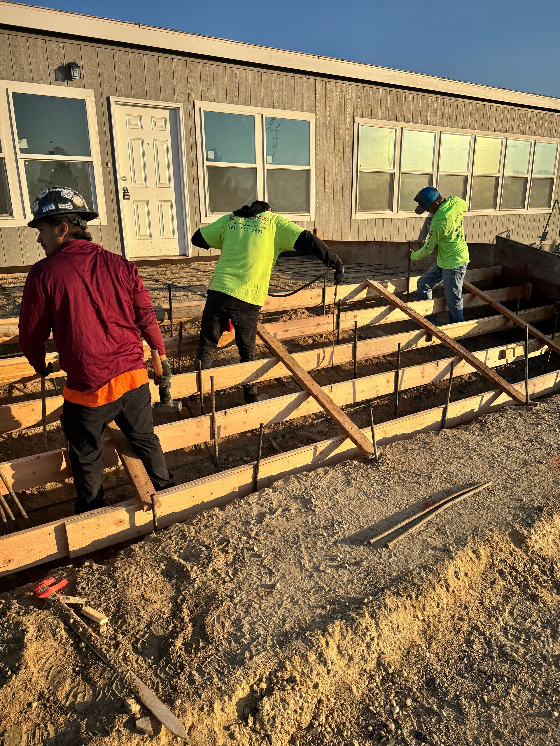 Construction workers pouring concrete steps in front of a building.