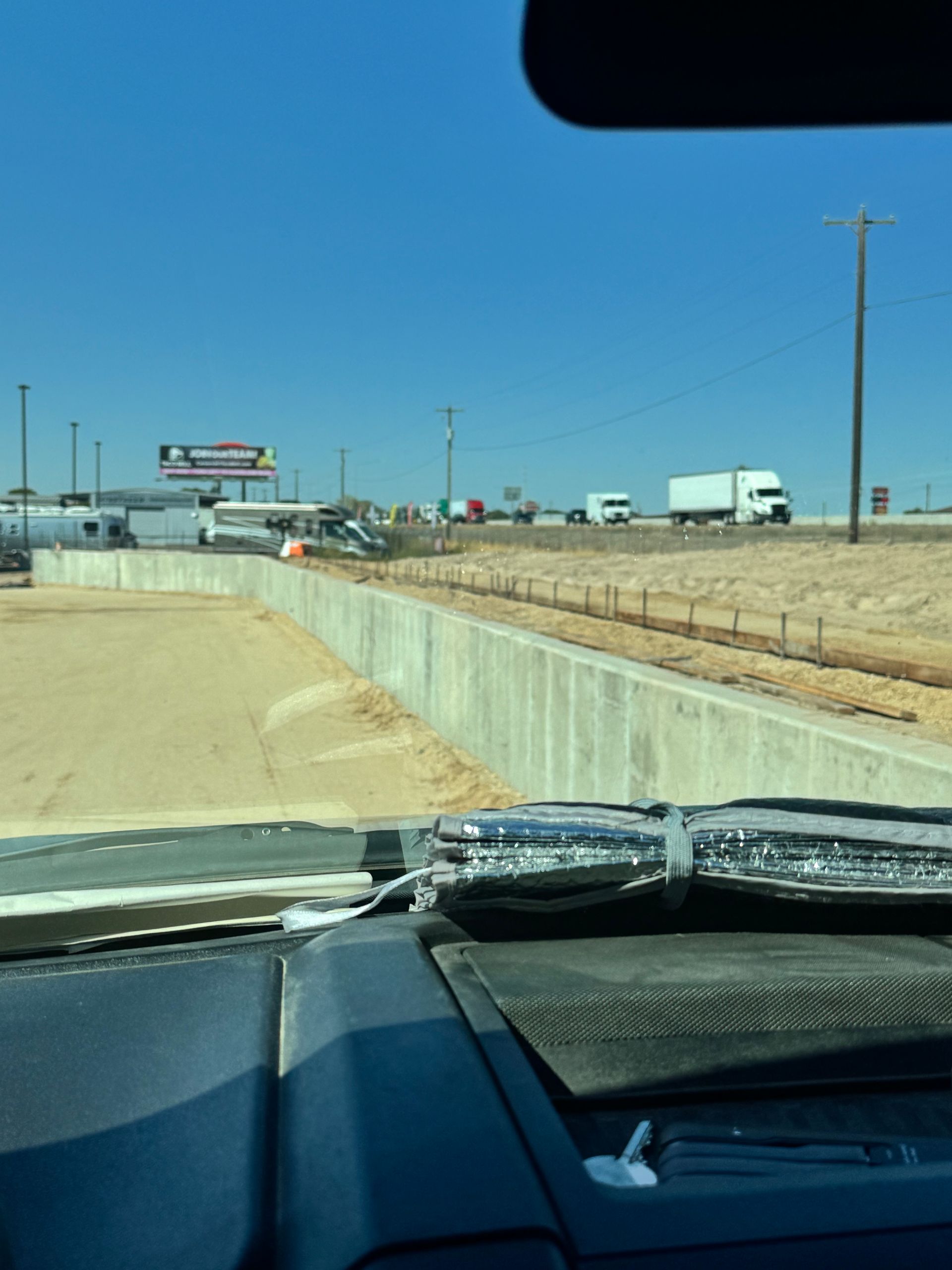 View from inside a vehicle, a concrete barrier next to a highway. 