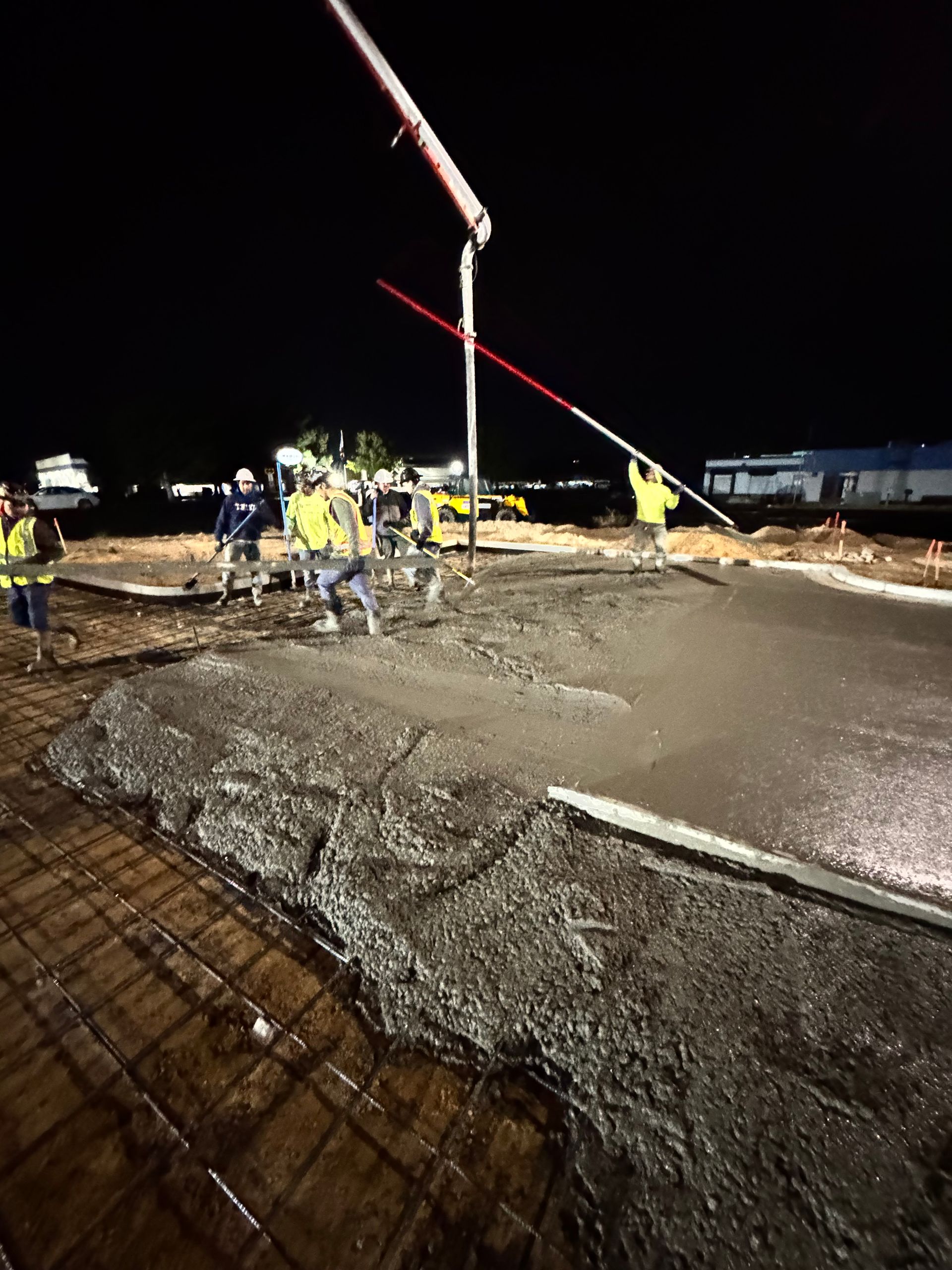 Construction workers pouring concrete at night. 