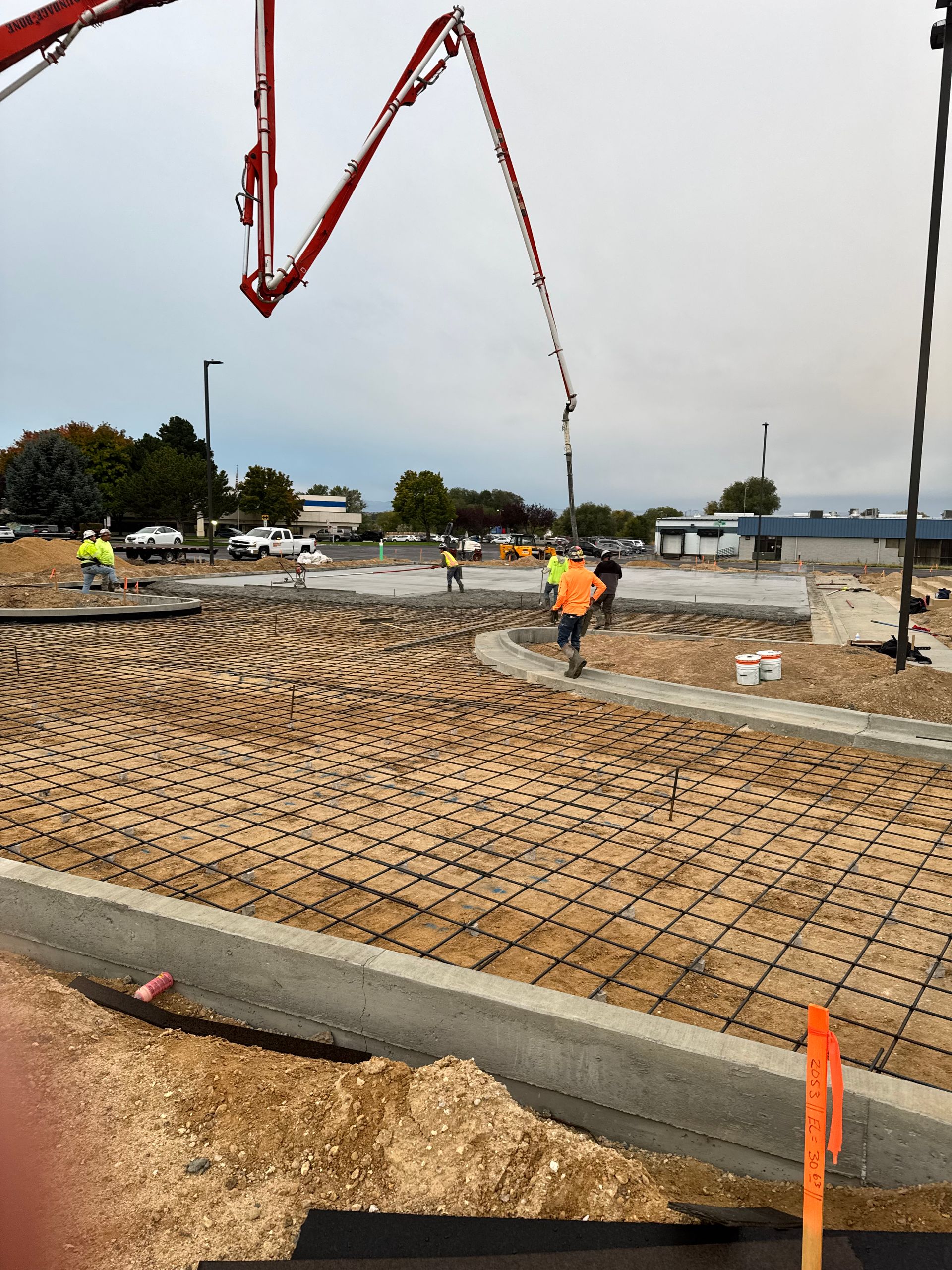 Concrete being poured over rebar on a construction site; workers in safety vests.